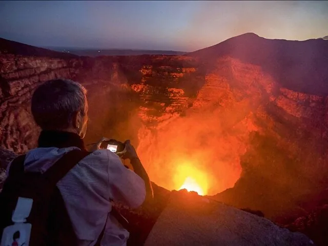 Eine Person fotografiert die glühende Lava im Krater des Vulkans Masaya.