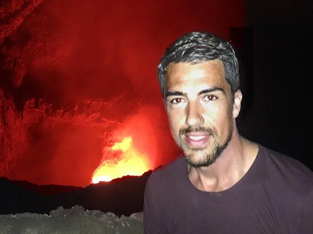 Mann, der ein Selfie mit der leuchtenden Lava des Vulkans Masaya im Hintergrund macht.