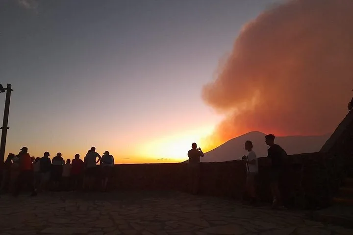 Silhouetted tourists watching the sunset and glowing smoke at Masaya Volcano.
